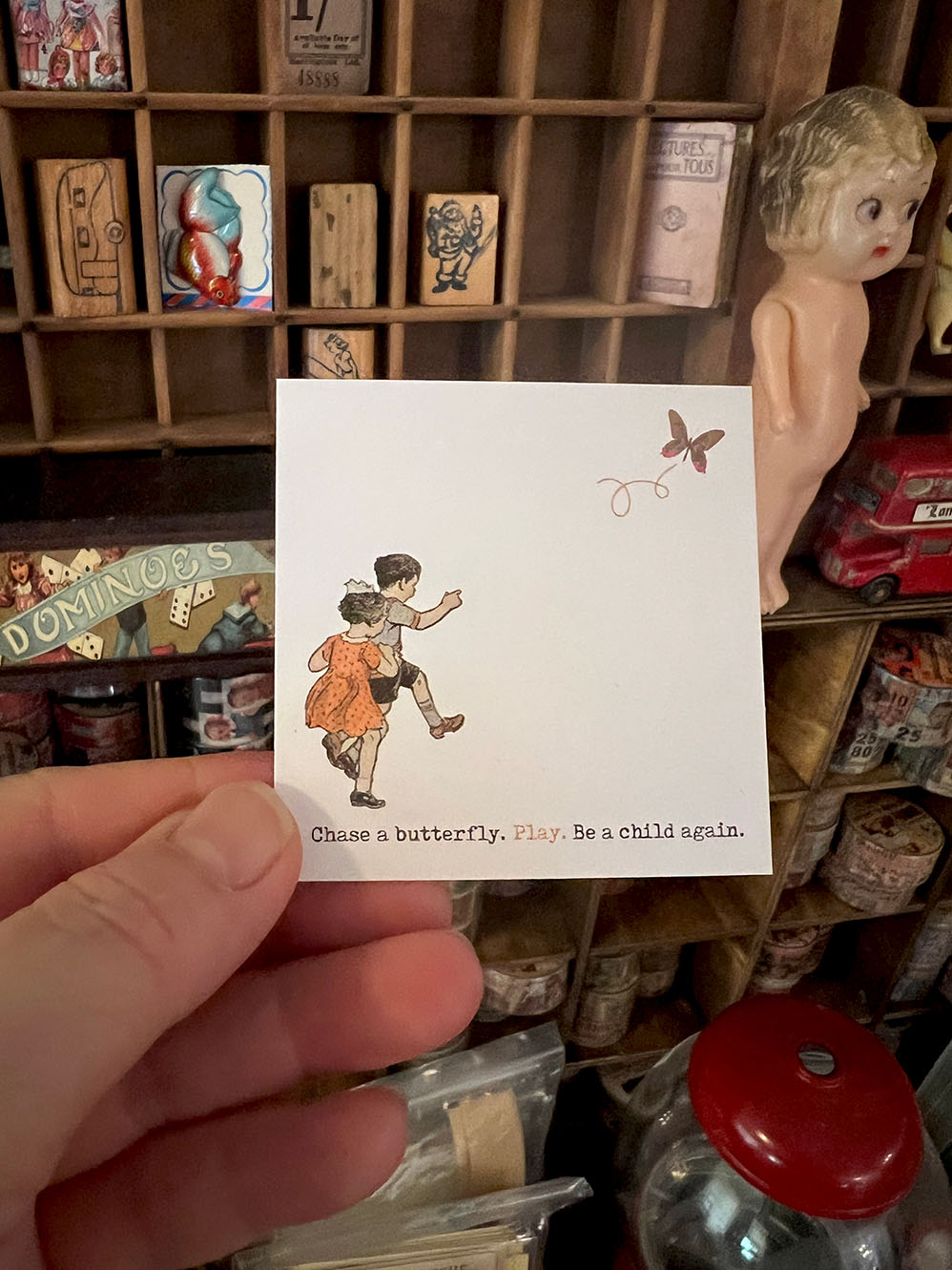 Small card with illustration of two children chasing a butterfly held in front of vintage wooden drawers. 'Chase A Butterfly' Journal Card Set (Happy Days series) from micmoc.com at Mic Moc