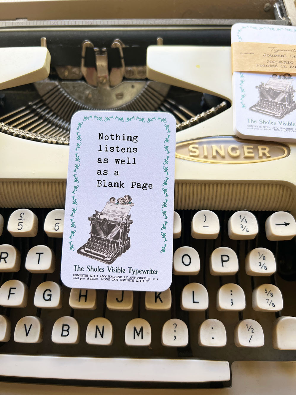 Vintage typewriter with a journal card featuring the quote 'Nothing listens as well as a blank page'. Typewriter journal card from micmoc.com
